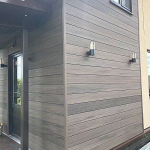 Готовый фасад частного дома, облицованный террасной доской ДПК Бамберг Square пустотелая. Цвет Бразильский орех (Brazilian Walnut), поверхность Окаменелое дерево (Fossiled).